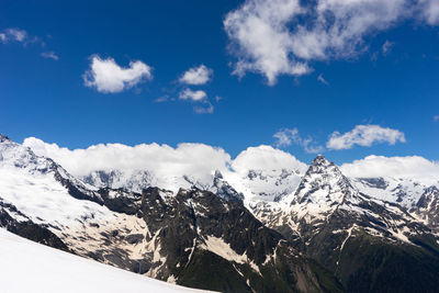 Scenic view of snowcapped mountains against blue sky