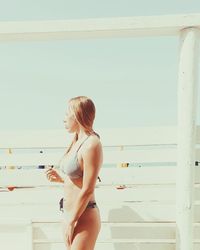 Woman standing by sea against sky