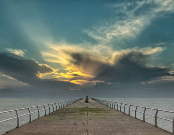 Pier over sea against sky during sunset