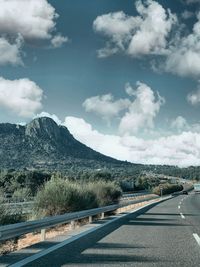 Road by mountains against sky