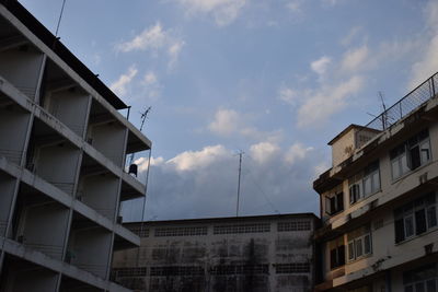 Low angle view of buildings against cloudy sky