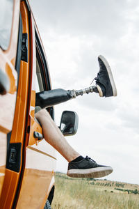 Legs of prosthetic young man dangling out of camper van window