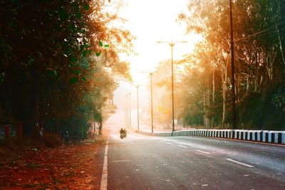 Road amidst trees in city against sky