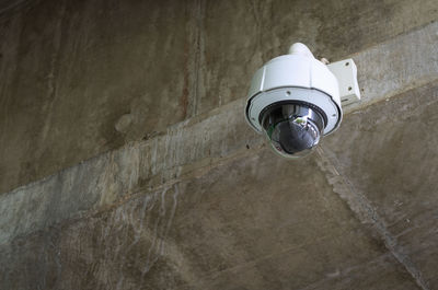 Low angle view of electric lamp on wall, closed-circuit camera