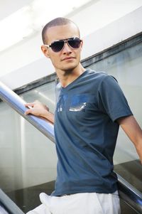 Young man wearing sunglasses standing on staircase