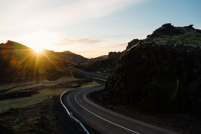 Road by mountain against sky during sunset