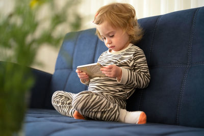 Cute girl playing with toy sitting on sofa at home