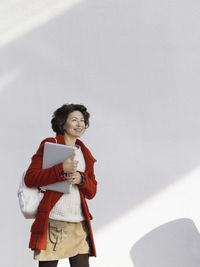 Woman is walking by white wall.student with laptop.freelancer with device for work.modern lifestyle.