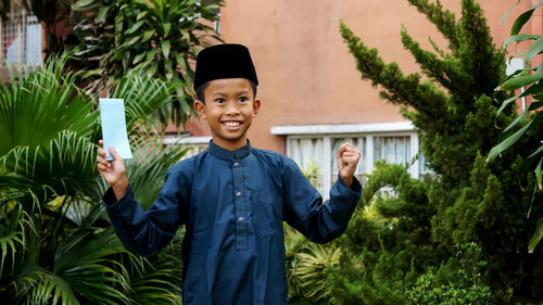 Portrait of a smiling young man standing by plants