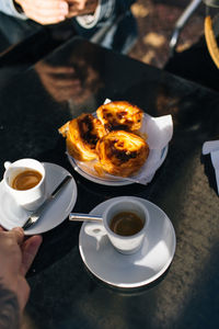 Close-up of hand holding cappuccino served on table