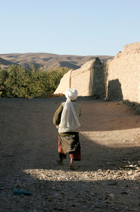 Rear view of man walking on umbrella against sky