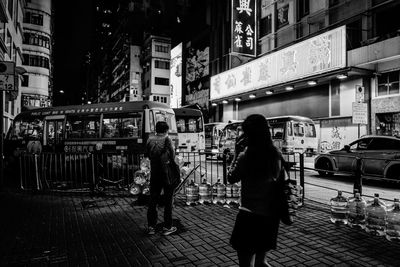 Rear view of people walking on street at night