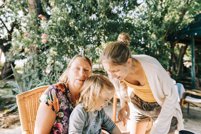 Girl sitting with grandmother against trees