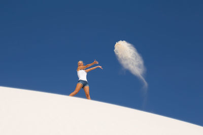 Low angle view of woman standing against blue sky