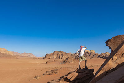 Man standing on desert against clear blue sky