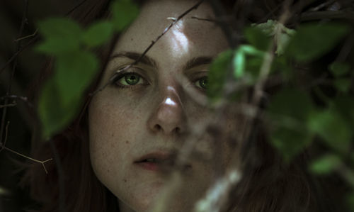 Close-up portrait of young woman amidst plant