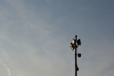 Low angle view of bird perching on street light against sky