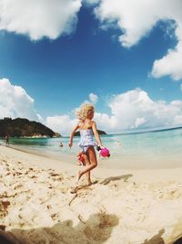 Rear view of girl with toy running at sandy beach