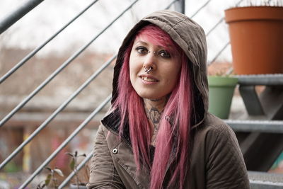 Portrait of smiling woman with pink hair and hooded shirt