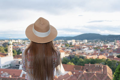 Rear view of woman looking at cityscape against sky