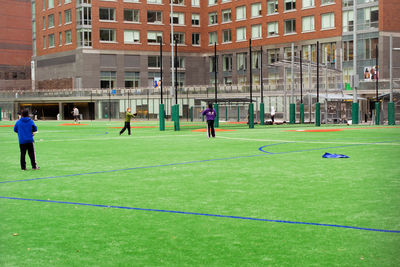 People playing soccer on field in city