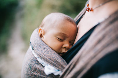 Midsection of mother carrying sleeping daughter in baby carrier