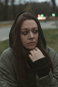 Crying young woman with running mascara on the street in twilight