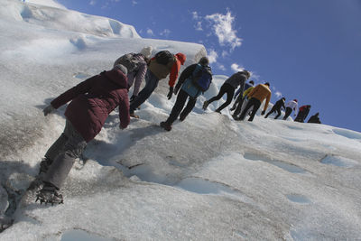 People on snow covered land against sky