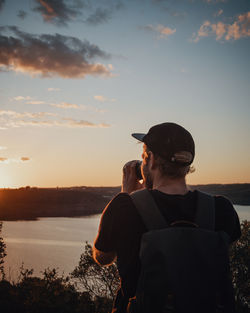 Man standing by sea against sky during sunset
