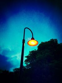 Low angle view of illuminated street light against blue sky