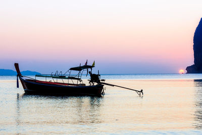 Fishing boat in sea against sky during sunset