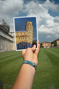 Low section of woman holding glass building against sky