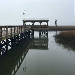 Pier on calm lake against clear sky