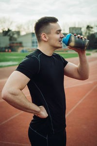 Athlete drinking water while standing on running track