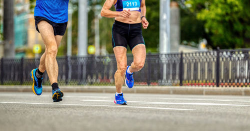 Legs men and women runners run down street marathon race together