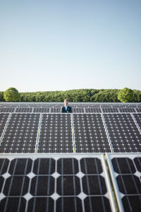 Mature man standing on panel in solar plant