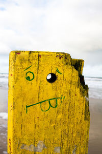 Close-up of yellow metal structure on beach against sky