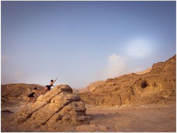 People on rock formation against sky