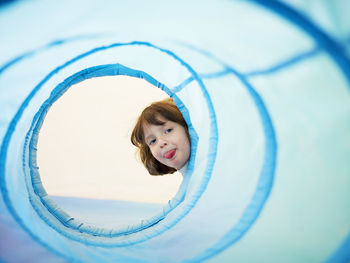 Portrait of girl looking through blue fabric