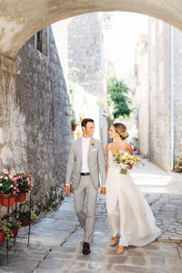 Couple holding flower bouquet against wall