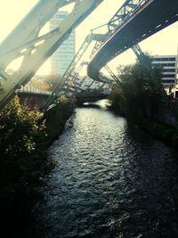 Footbridge over river in city against sky