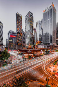 Traffic on road by buildings against sky in city