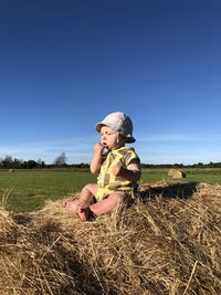 A little boy in a panama sits on a haystack in a hot summer on a big field. close-up.