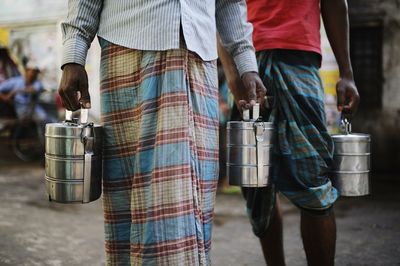 Mid section of men holding lunch box