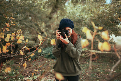 Young woman taking photos in the forest with an old analog camera