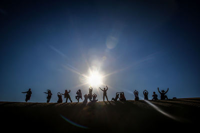 People gesturing on landscape against sky