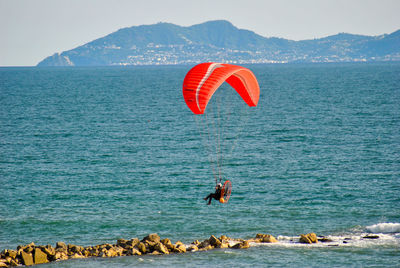 People on rock by sea against sky