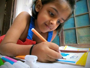 Close-up of girl drawing while sitting at home