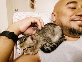 Close-up of man playing with kitten at home