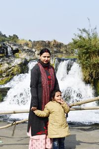 Portrait of woman and a baby standing against waterfall